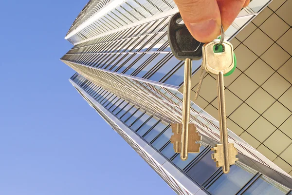 Die Schlüssel zum Büro auf dem Hintergrund eines Wolkenkratzers — Stockfoto