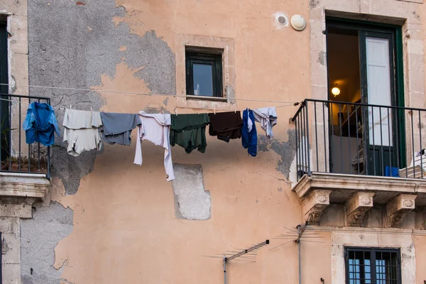 Wäsche, die zum Trocknen an einem Draht vor einer sehr verdorbenen Wand hängt Stockfoto