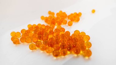Vitaminler, balık yağı, beyaz arka plana saçılmış altın turuncu renkler. İzole edilmiş. Seçici Odaklanma