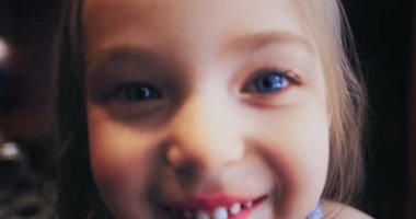 Görüntü dağılıma gidiyor. Kız kalın saçlı, arkasını dönüp kameraya bakan ve gülümseyen bir çocuk. Seçici odaklanma. Video odak dışı. Mutlu bir hayat konsepti.