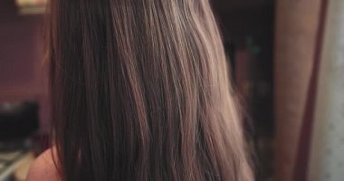 Bir kız kalın saçlı bir çocuktur. Saç ağır çekimde çekilir. Rüzgarda saç çıkıyor. Sağlıklı saç kavramı. Seçici odaklanma. Odada..