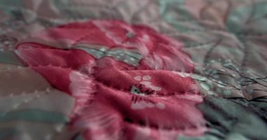 Çiçekli renkli kumaş. Desenli arka plan. Kumaştaki resmin dokusu yakın plan. Kumaş boyunca uçan bir kamera. Seçici odaklanma. 4K DCP
