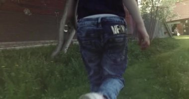 Vyazniki Rusya 01.06.2021 Güneşli bir yaz gününde çimlerde koşan bir kız bebek güneş ışınları, dinlenme, sebze bahçesi, doğa. 4K.