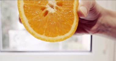 Kadınların eli sulu bir portakalı sıkar ve suyu dışarı akar. Sağlıklı yaşam tarzı kavramı. 4K