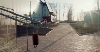 Bahar güneşli bir gün, pembe ceketli ve şapkalı genç bir kız rampada yürüyor. Odaklanamayan genç bir kız. 4K.