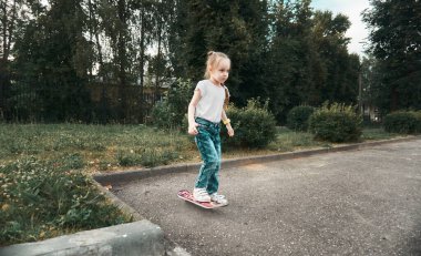 Bir kız uçan bir kaykaya biniyor. Spor ve eğlence için manyetik kaykay. Yaz, yürüyüş ve spor zamanıdır.