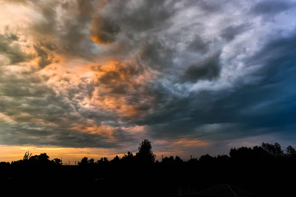 Belo panorama natural da paisagem noturna. Telhados de silhueta de casas e árvores. Nuvens Hembic no por do sol, cores coloridas brilhantes da natureza — Fotografia de Stock