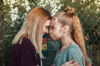 Annemin kızı alınlarıyla birbirine dokunuyor, birbirine bakıyor ve gülümsüyor. Çocuklar ve ebeveynler arasındaki ilişki. Geçiş yaşı, büyüme dönemi..