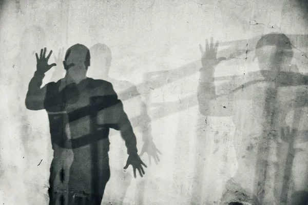 White textured wall with human shadow. Silhouette of a man with spread hands. Abstraction, horror, thriller.