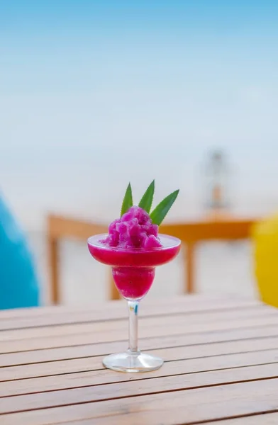 Kum ve plaj arka planında meyve dilimleri olan ejderha meyveli smoothie. seçici odak (görünümü kapat)