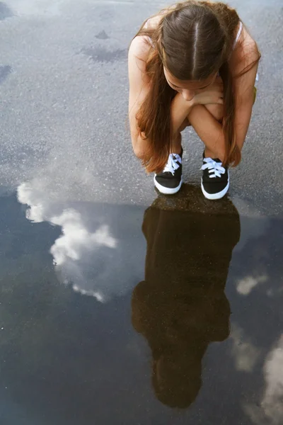 Little girl sit down near pool after rain — Stock Photo, Image