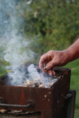 Bir erkek el altında bir kamp ateşi başlatmak için çıra ahşap parça tutar.