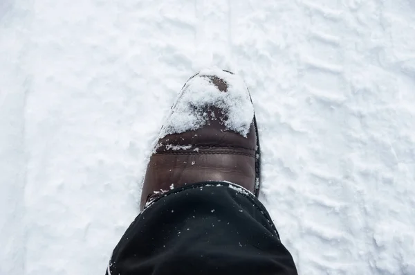 Brown leather shoe, boot in winter in white snow, winter