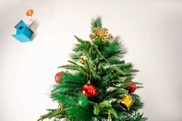 Arka planda süslü Noel ağacı ve mavi kuş evi var.