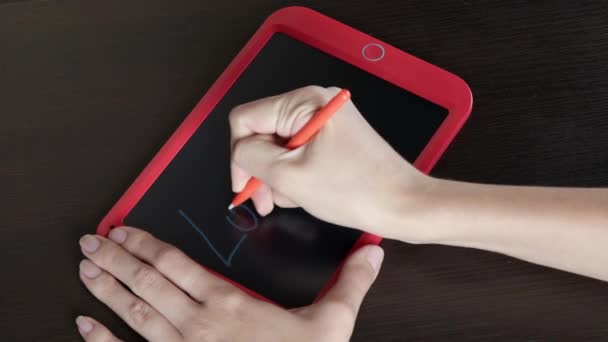 Uma menina close-up escreve uma palavra em um tablet - Carregando... — Vídeo de Stock