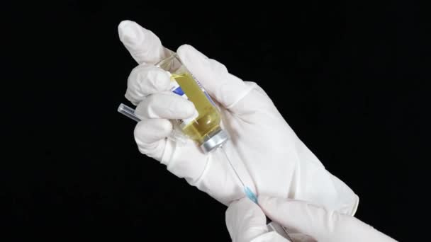 Eine Frau mit weißen Handschuhen zieht den Impfstoff in eine Spritze — Stockvideo