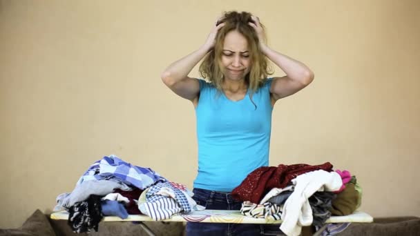 Уставшая депрессивная домохозяйка собирается погладить свою мятую одежду — стоковое видео