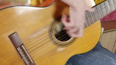 Bir kadın gitar çalıyor, tellere vuruyor.