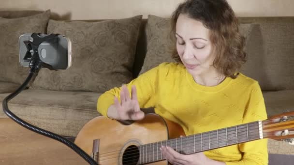 Una mujer enseña a tocar la guitarra — Vídeos de Stock