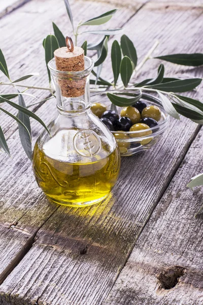 Brocca con olio extravergine di oliva su tagliere circondata da rami — Foto Stock