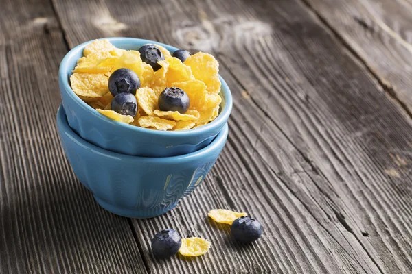 Desayuno saludable. Cuencos de cerámica porcionados azules con copos de maíz arándanos frescos — Foto de Stock