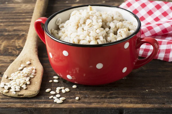 The red ceramic saucepan with white polka dots complete crumbly barley porridge — Stock Photo, Image