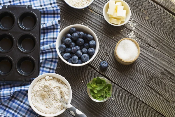 Zdravé domácí koláče. Ingredience na borůvkové muffiny na tmavém pozadí dřevěná — Stock fotografie