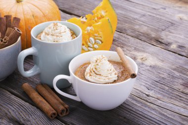 Quick meal breakfast snack in the microwave. Fragrant homemade pumpkin pie fall for five minutes in the cup portions with whipped cream and cinnamon on a wooden background clipart