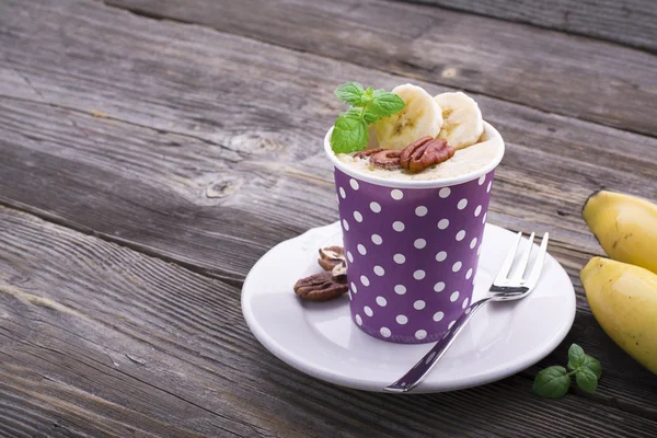 Snabb frukost i mikron i fem minuter. Hemgjord banan kopp kakor i pappersmuggar portioneras mellanmål. två delar med pecan och skivor, färsk mynta — Stockfoto