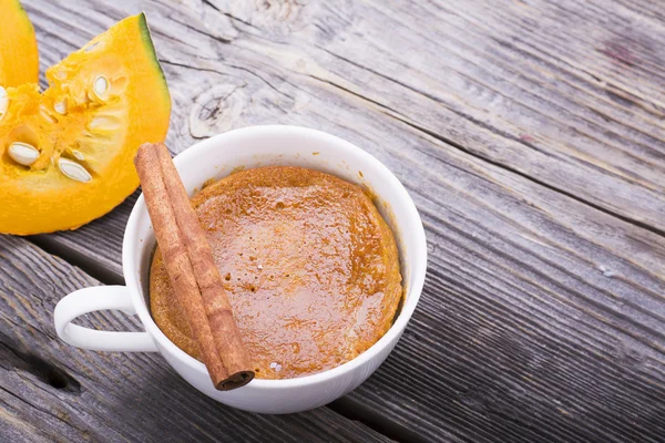 Repas rapide petit déjeuner en collation au micro-ondes. Tarte à la citrouille maison parfumée tomber pendant cinq minutes dans les portions de tasse avec crème fouettée et cannelle sur un fond en bois — Photo