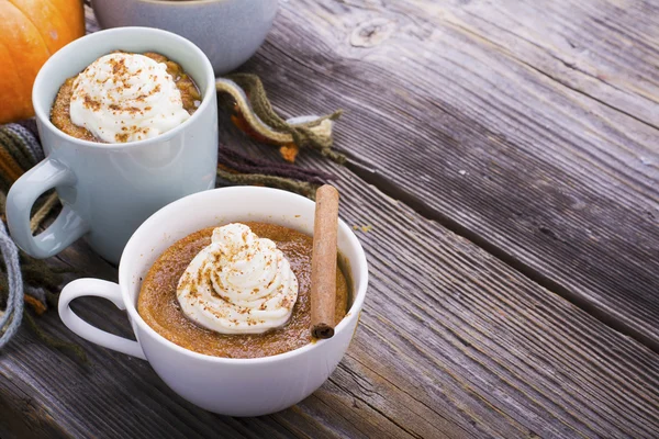 Repas rapide petit déjeuner en collation au micro-ondes. Tarte à la citrouille maison parfumée tomber pendant cinq minutes dans les portions de tasse avec crème fouettée et cannelle sur un fond en bois — Photo