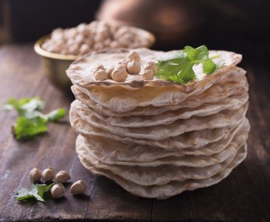 Vegetarinskogo ve sağlıklı beslenme için nohut unu ile yararlı ev kek Kule ince gevrek somun. Koyu ahşap arka plan üzerinde kişniş nohut kuru sprigs.