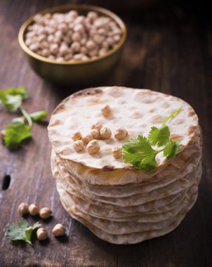 Vegetarinskogo ve sağlıklı beslenme için nohut unu ile yararlı ev kek Kule ince gevrek somun. Koyu ahşap arka plan üzerinde kişniş nohut kuru sprigs.