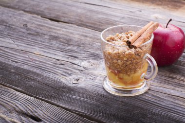 Mikrodalgafırında birkaç dakika hızlı kahvaltı atıştırmalık. Yüksek ahşap gri arka plan üzerinde şeffaf hızlı bir şekilde karamel sos krem şanti ile kupa geleneksel elmalı turta. seçici odaklama