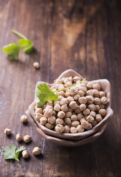 Los garbanzos secos para un hogar saludable y recetas vegetarianas en cuenco de cerámica hecha a mano forma inusual en simple fondo oscuro de madera rústica —  Fotos de Stock