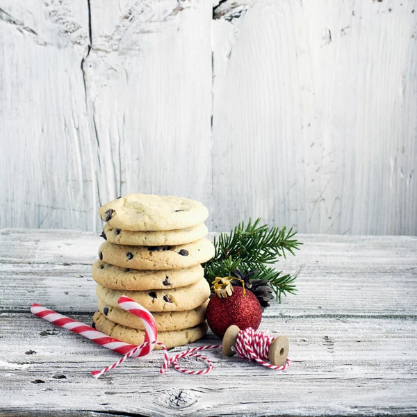 Carte de Noël festive. Biscuits faits maison avec des gouttes de chocolat pour le Père Noël dans le plat de cuisson est décoré branches de sapin, boules rouges, cônes, bonbons rayés personnel. focus sélectif — Photo