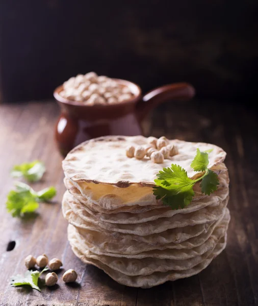 Věž má tenké křupavé bochníky užitečných domácích koláčů s moučkou z mouky pro vegetariány a zdravé jídlo. Na tmavém dřevěném pozadí koriandru cizrna suchá. — Stock fotografie