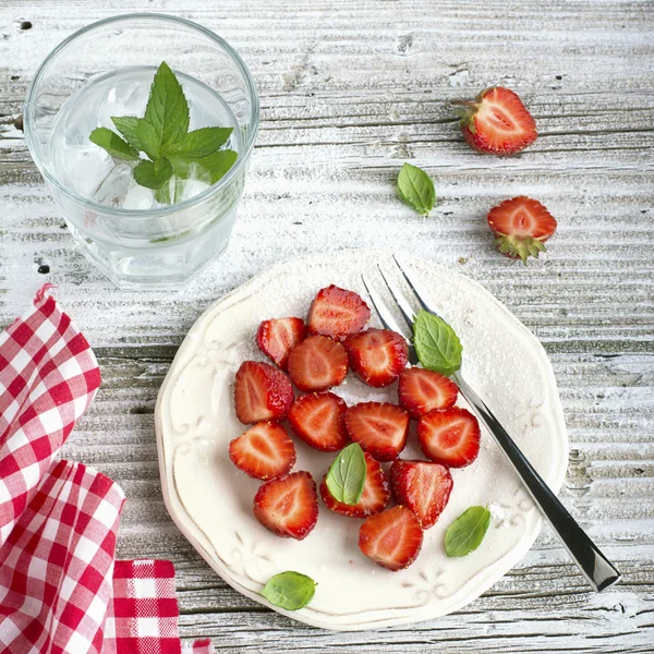 Gesunder leichter Frühstückssnack. Erdbeerscheiben mit Zucker, Basilikum, Minze zum Dessert auf Holzgrund. — Stockfoto
