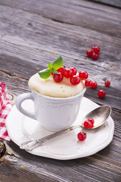 Snabb frukost mellanmål i mikrovågsugnen för ett par minuter. Mugg mannagryn tårta med röda vinbär på trä bakgrund. selektivt fokus — Stockfoto