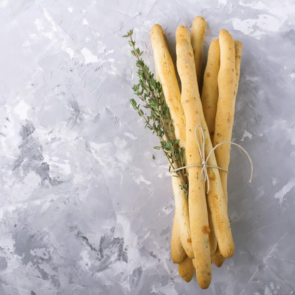 Bâtonnets de pain croustillant maison frais avec du thym et du sel de mer sur un fond de béton gris herbes. focus sélectif — Photo