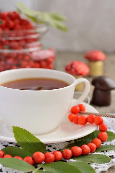 Tasse de thé et perles de rowan sur une table en bois — Photo