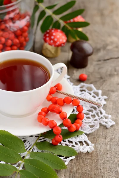 Cup of tea and rowan beads on a wooden table — Stock Photo, Image