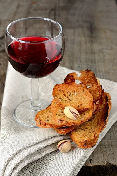 Tunn krutonger pistaschmandlar och ett glas rött vin — Stockfoto