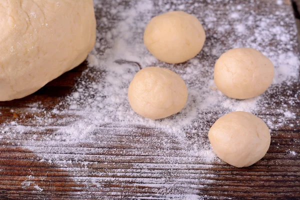 Small balls of fresh homemade dough on floured wooden board — Stock Photo, Image