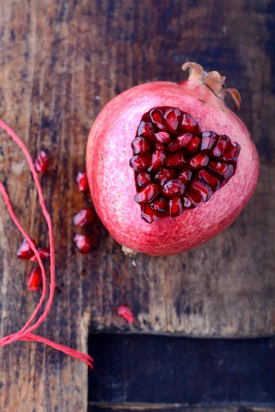 Semi di melograno nella forma di cuore su uno sfondo di legno . — Foto Stock