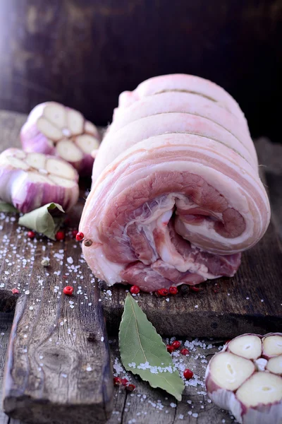 Rolo assado de carne de vitela crua em tábua de corte de madeira com alho — Fotografia de Stock