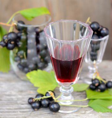 Siyah frenk üzümü likör ve ahşap masa üzerinde olgunlaşmış meyveler