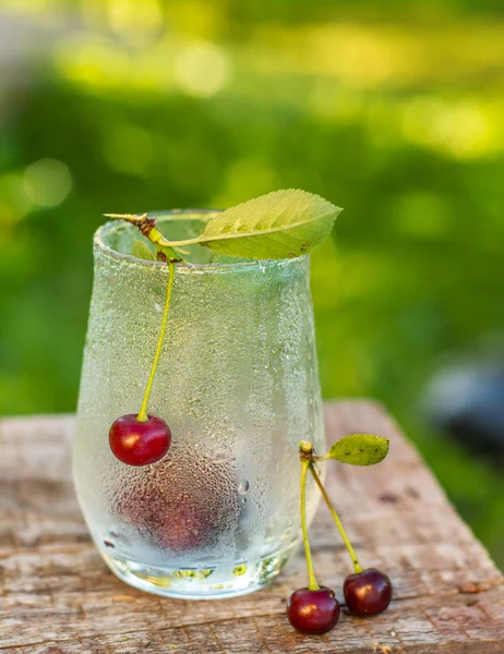 Glas met druppels dauw en kersen — Stockfoto