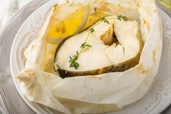 Filetes de bacalao cocidos en papel pergamino con rodajas de limón —  Fotos de Stock