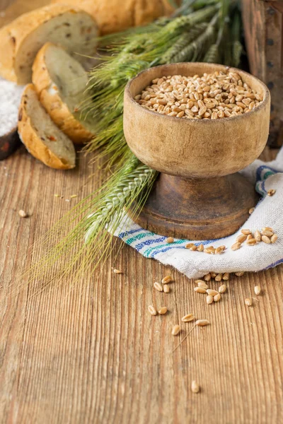 Ears of barley flour, bread on a wooden background — Stockfoto